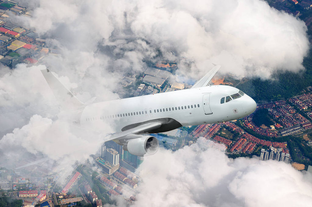 Αεροπλάνο που φέρουν ουρανό. Αεροπλάνο πάνω από την πόλη. Λευκό επιβατικά αεροσκάφη ανεβαίνει μέσα από τα σύννεφα. Αεροπλάνα και πόλεις. Μεταφορές και ταξίδια. Μαλαισία. - Φωτογραφία, εικόνα