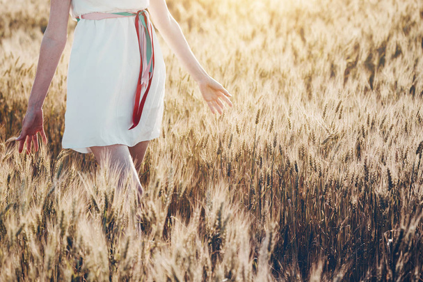 Tyttö kävelee pellolla ja koskettaa vehnää hänen han
 - Valokuva, kuva