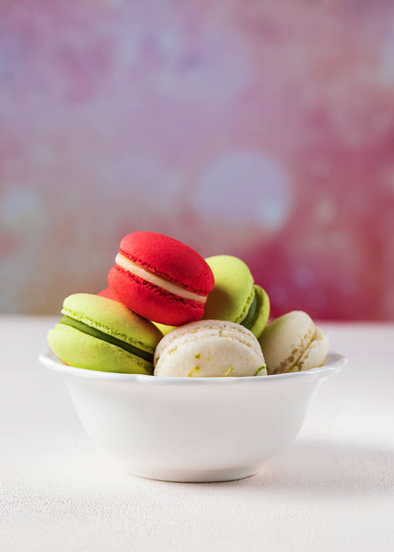 Biscotti macarons colorati in ciotola bianca su sfondo pastello, copiare spazio. Concentrazione selettiva. Un'immagine fresca e femminile. Verticale
. - Foto, immagini