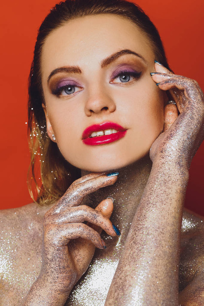 High fashion model girl in colorful bright spangles, glitter, in the studio on a red background, portrait of a beautiful sexy woman, fashionable glowing makeup. Colorful Brilliant Bright Makeup - Photo, Image