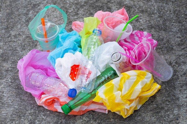 Resíduos de plástico colorido, sacos, copos, garrafas, palhas no fundo do piso de cimento
 - Foto, Imagem
