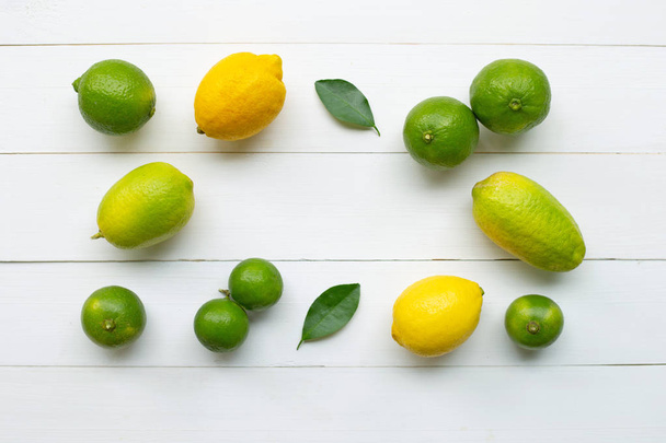 Citrons mûrs et citrons verts sur fond de bois blanc
. - Photo, image
