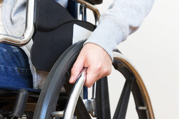 Detail of disabled woman holding a hand on wheel of a wheelchair. Close up. - Photo, image