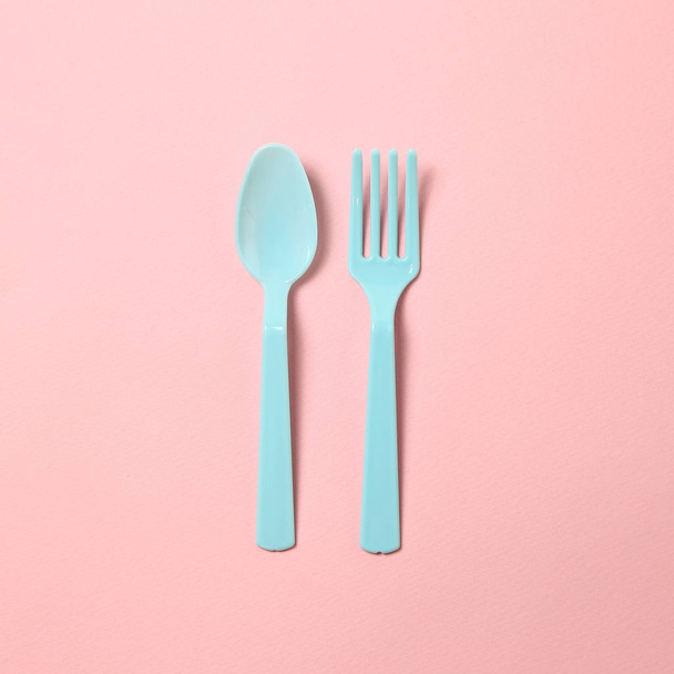 Μπλε πλαστικό πιρούνι και κουτάλι που απομονώνονται σε ροζ φόντο - Φωτογραφία, εικόνα