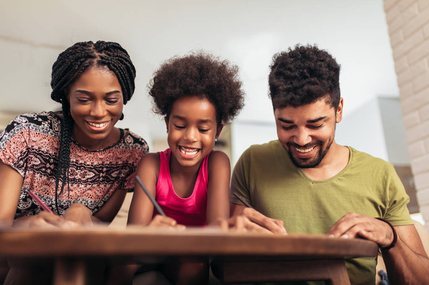 Mom and dad drawing with their daughter. African american family spending time together at home. - Foto, Imagen