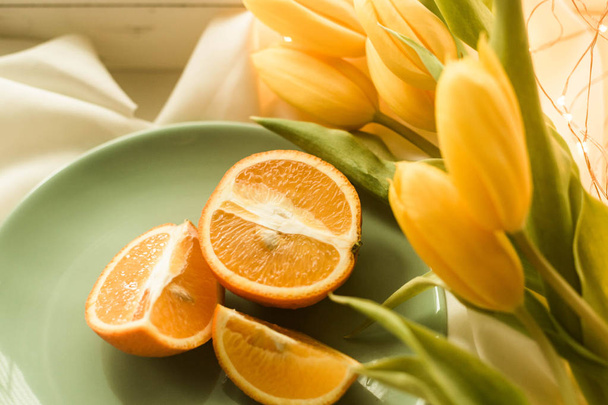 Київ (Україна)-29 березня 2018 роки: На фото є щойно нарізаний помаранчевий на тарілку прикрасити жовті тюльпани. - Фото, зображення
