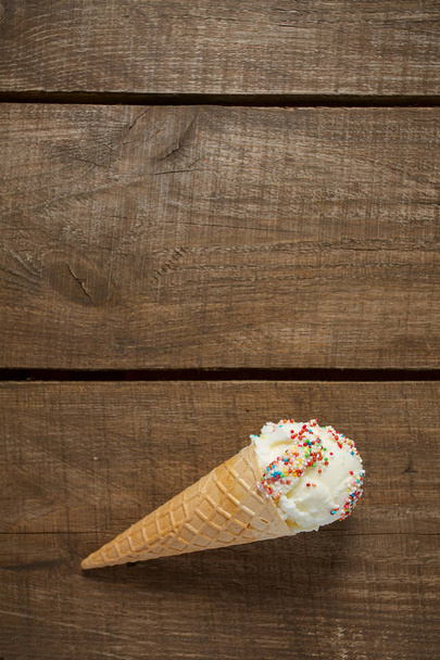 ванільне морозиво у вафельних конусах над дерев'яною поверхнею
 - Фото, зображення