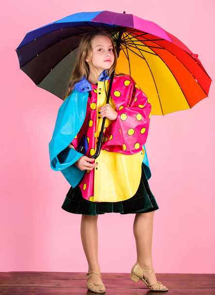 Confident in her fall garments. Waterproof accessories manufacture. Kid girl happy hold colorful umbrella wear waterproof cloak. Waterproof accessories make rainy day cheerful and pleasant - Photo, image