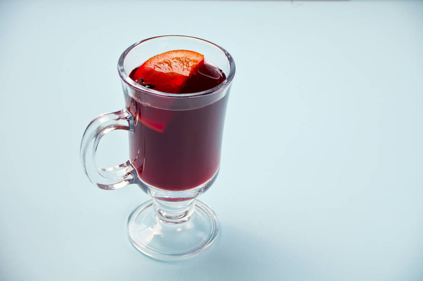 Wineglass with Christmas mulled red wine with spices and fruits on a blue background. - Foto, afbeelding