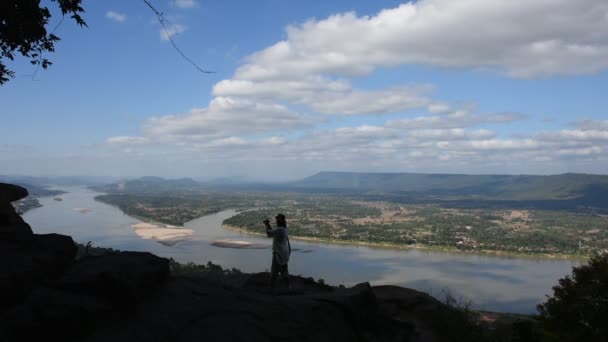 Asian thai woman travel visit and shooting photo view of landscape of Nongkhai city and loas and Mekong river on ridge stone of cliffs at Wat Pha Tak Suea temple in Nong Khai, Thailand - Footage, Video