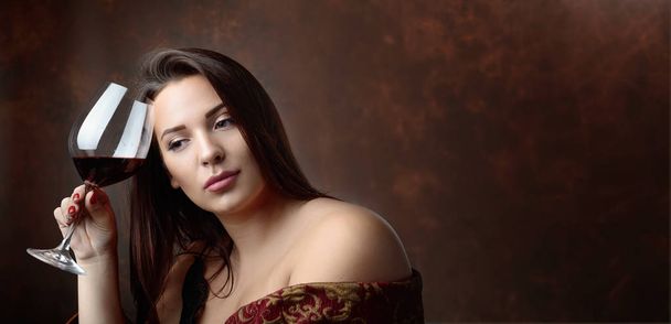 Kırmızı şarap ile güzel bir genç kadın portresi. Mükemmel makyaj ve saç. Modeli artı boyutu. Kopya alanı. - Fotoğraf, Görsel