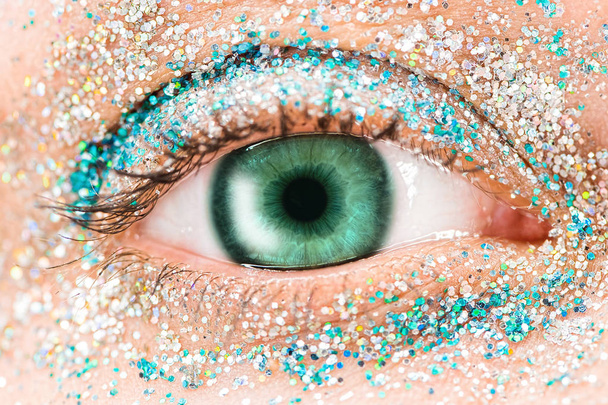 Macro green female eye with glitter eyeshadow, colorful sparks, crystals. Beauty background, fashion glamour makeup concept. Holiday evening make-up detail. - Fotoğraf, Görsel