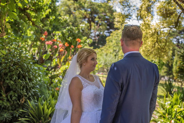 Just married couple wearing wedding dresses posing in beautiful green garden. Shot at wedding in Australia on amazing sand beach. - Fotó, kép