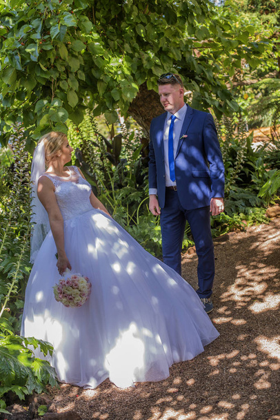 Gerade verheiratete Paare, die im Garten stehen und einander anschauen. Aufnahme bei einer Hochzeit in Australien am traumhaften Sandstrand. - Foto, Bild