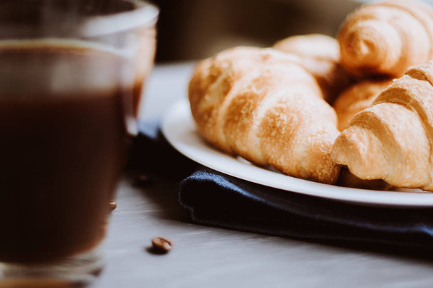 Dessert and coffee beans. Mate moody color. Macro shot of fresh croissants and coffee on a black background. The concept of breakfast. - 写真・画像