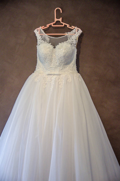 Piękny biały ślub sukienka wisi na plastikowy wieszak czekam na panny młodej. Strzał na weselu w Australii na niesamowite plaży piasek. - Zdjęcie, obraz