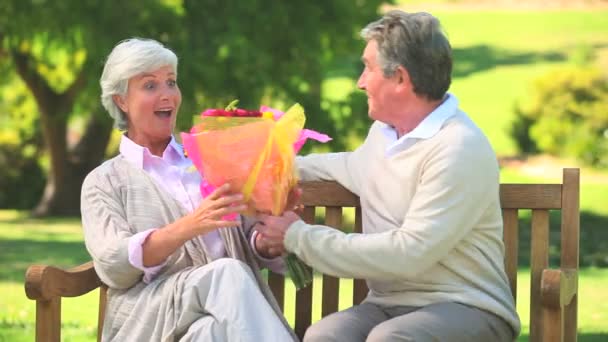 Mature man giving a bunch of flowers to his wife - Materiał filmowy, wideo