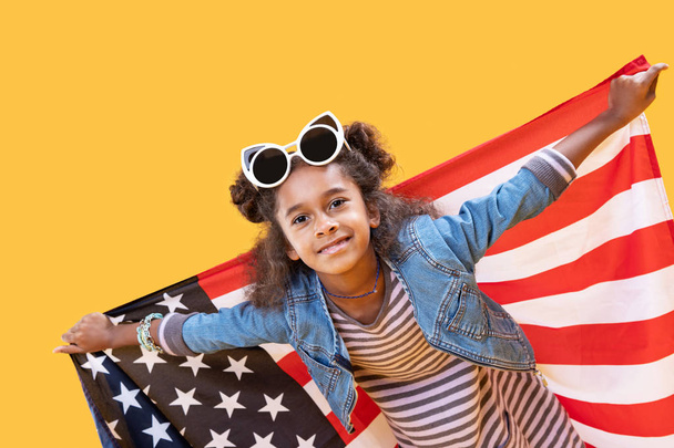 Chica alegre positiva de pie con una bandera de EE.UU.
 - Foto, imagen