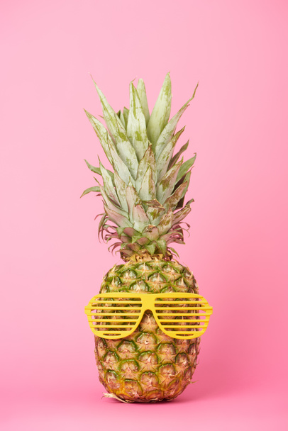 funny and tasty pineapple in sunglasses on pink background - Фото, изображение