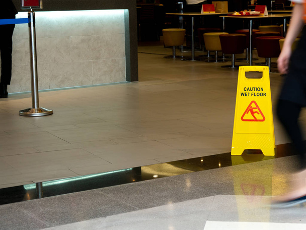 デパートのレストランでぬれた床の警告を示す看板と黄色いプラスチック コーン - 写真・画像