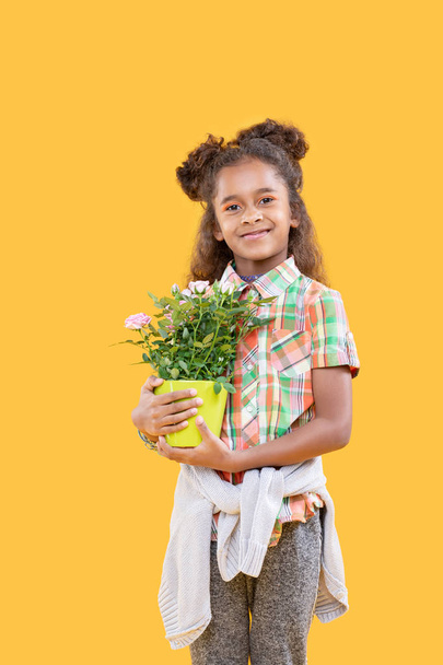 Cheerful delighted girl holding her favourite flower - Foto, imagen