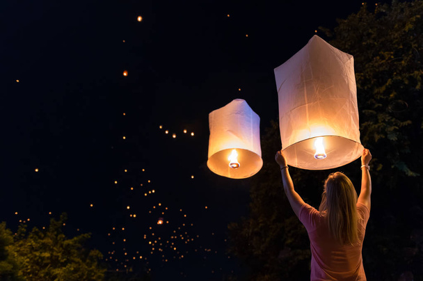 Woman releasing lantern in the Loy Krathong festival or floating lanterns festival in Chiang Mai, Thailand. - Photo, image