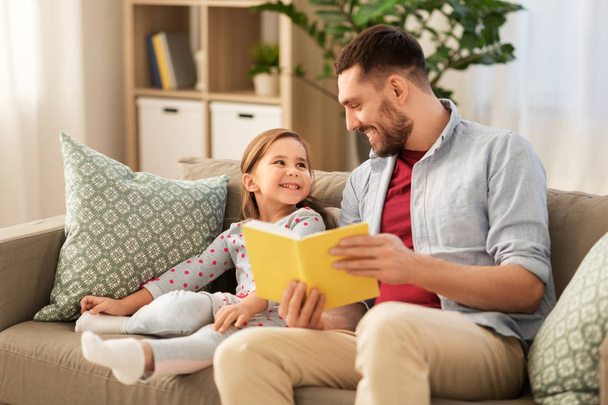happy father and daughter reading book at home - Photo, image