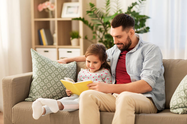 happy father and daughter reading book at home - Fotoğraf, Görsel