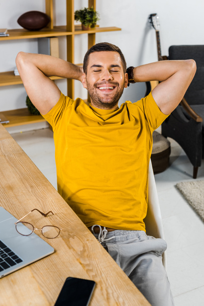 homem alegre sentado na cadeira e sorrindo em casa
  - Foto, Imagem