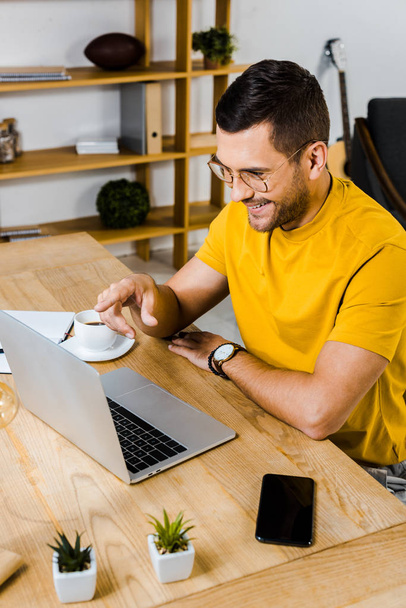 cheerful man pointing with finger at laptop at home - Photo, Image