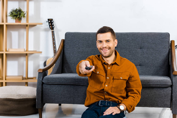 happy man holding remote control at home  - Valokuva, kuva