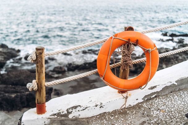 Red emergency lifebuoy hanging on fence near beach  - Fotografie, Obrázek