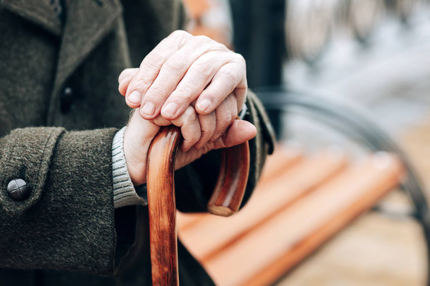 Nahaufnahme eines Rentners, der sich auf einen Gehstock stützt - Foto, Bild
