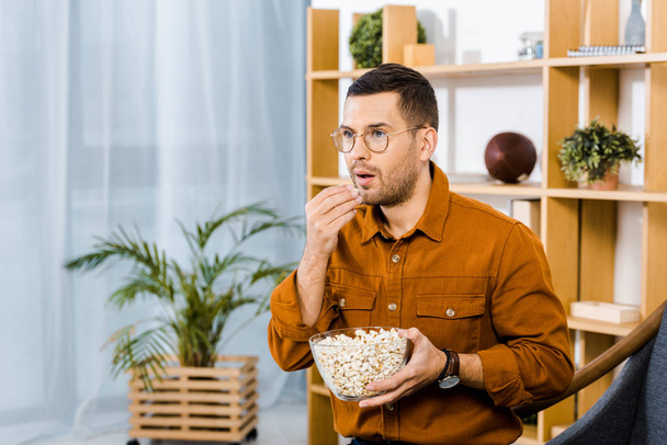 surprised man in glasses eating popcorn while watching movie  - Fotó, kép