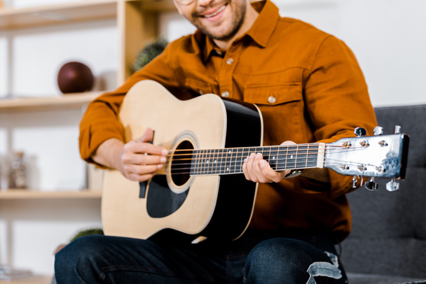 cropped view of cheerful man playing acoustic guitar - 写真・画像