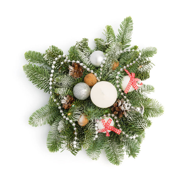 Christmas decoration consisting of fir twigs, shiny balls, cones around the candle, covered with snow on a white background. Top view - Photo, Image