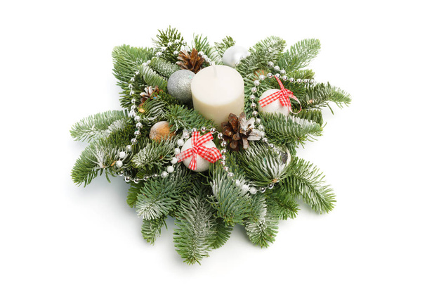 Weihnachtsdekoration aus Tannenzweigen, glänzenden Kugeln, Zapfen rund um die Kerze, mit Schnee bedeckt auf weißem Hintergrund - Foto, Bild