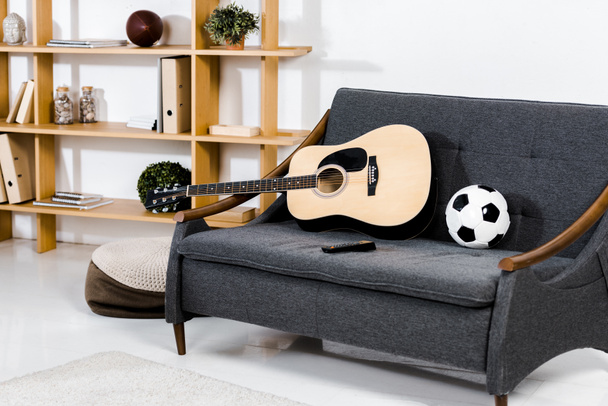 modern living room with acoustic guitar, ball and remote control on sofa  - Fotoğraf, Görsel