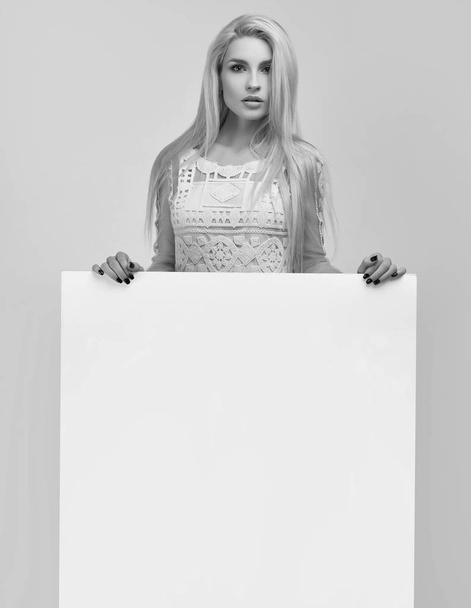 Retrato de una hermosa mujer rubia sosteniendo un cartel en blanco aislado sobre fondo blanco en el estudio
 - Foto, imagen