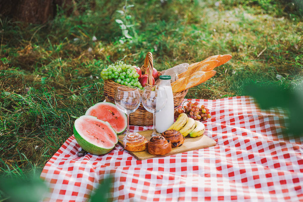 Healthy food for picnic outside. View from above of fresh buns, bread, yogurt, bananas, watermelon, green grape and red apples. Horizontal color image. - Photo, Image