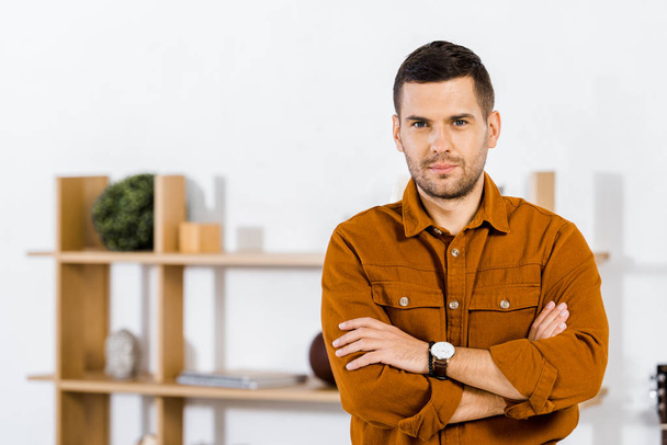 handsome man standing with crossed arms in living room  - Photo, image