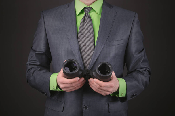 Binoculars in a businessman hands on a dark black background. - Фото, зображення