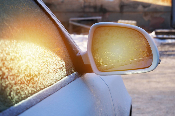 beautiful frosty patterns in the rearview mirror on the glass of the car and the glare of the sun - Fotoğraf, Görsel