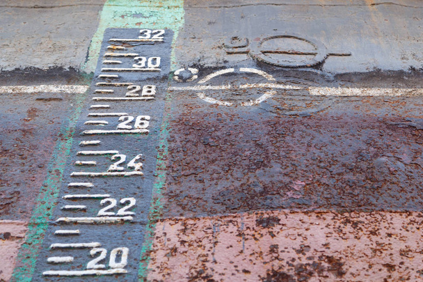Uitwatering markering en ontwerp schalen op de roestige romp van het schip in droge docking tijdens reparaties - Foto, afbeelding