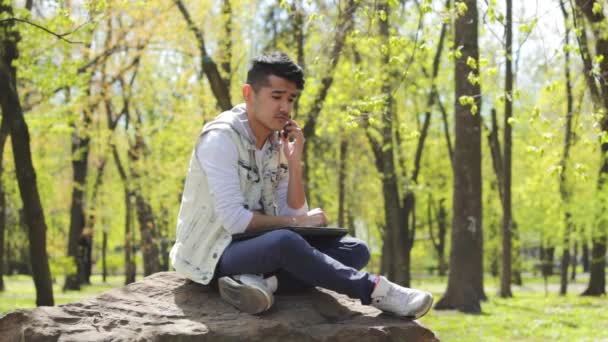 Νεαρός άνδρας μιλώντας από τηλεφώνου στο πάρκο - Πλάνα, βίντεο