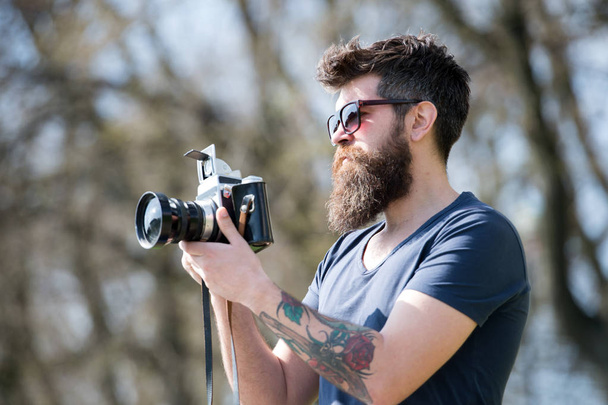 Man bearded hipster photographer hold vintage camera. Photographer with beard and mustache amateur photographer nature background. Man with long beard busy with shooting photos. Photographer concept - Fotografie, Obrázek