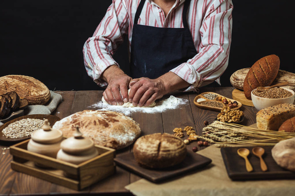 Gros plan des mains de boulanger pétrissant la pâte et faisant du pain avec un rouleau à pâtisserie
. - Photo, image