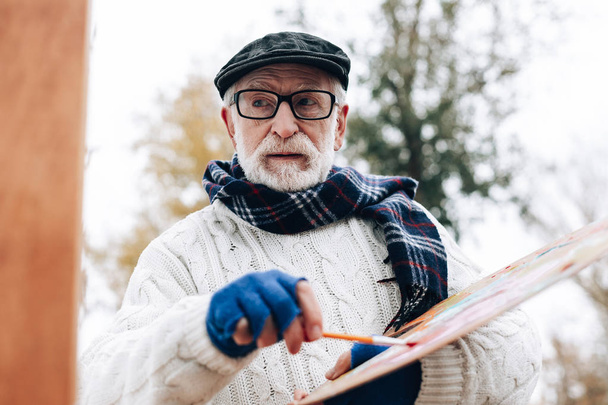 Portrait of handsome pensioner that mixing colors - Фото, изображение