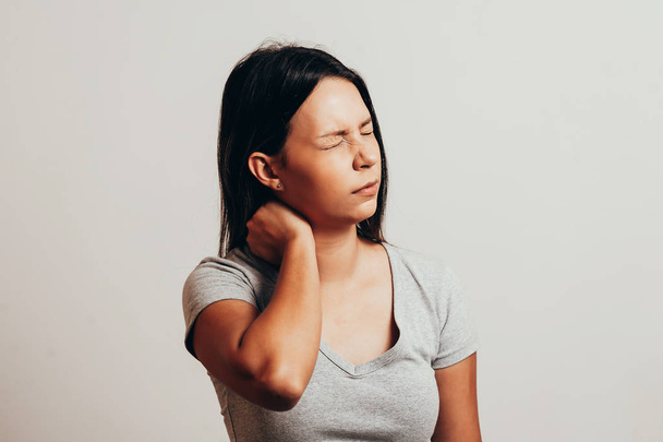 Молодая женщина с болью в шее на сером фоне
 - Фото, изображение