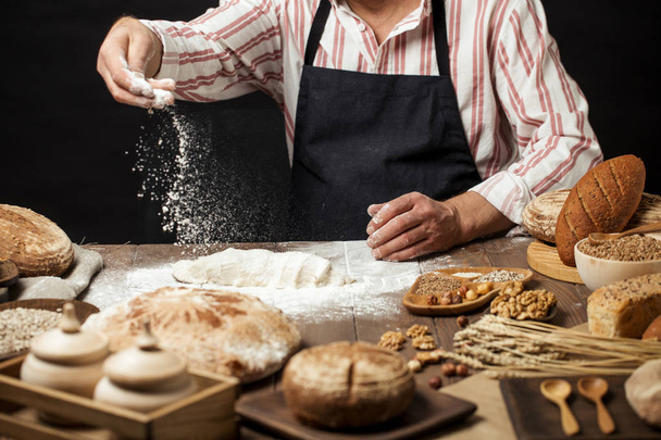 Man sprinkling some flour on dough. Hands kneading dough, cropped view - Fotoğraf, Görsel